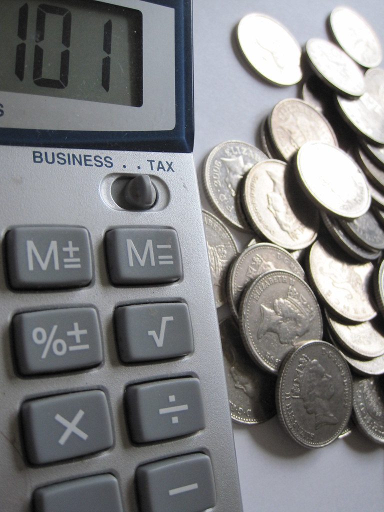 A calculator next to a stack of coins on a desk